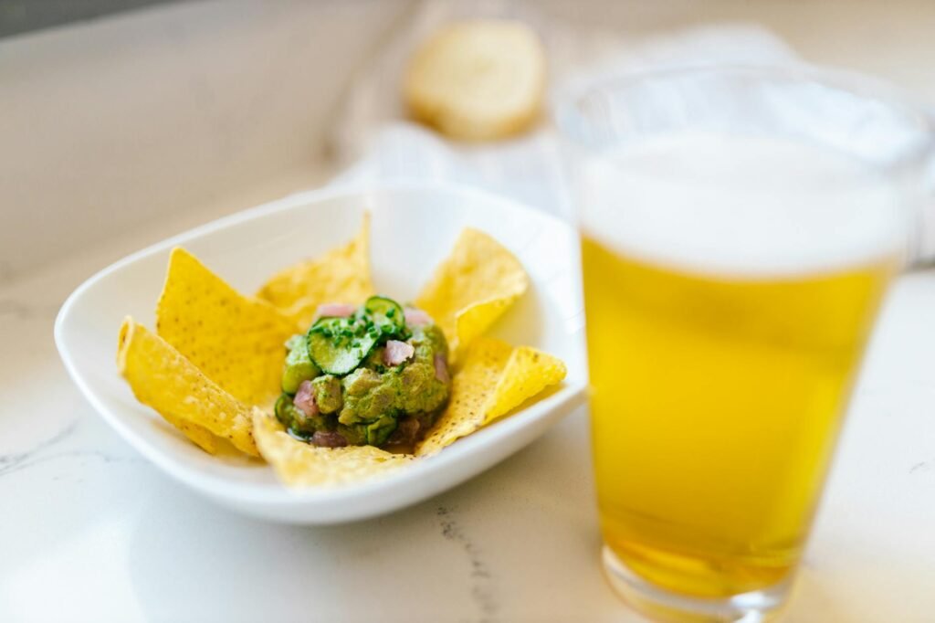 Glass bowl of guacamole with plastic wrap pressed directly onto the surface.