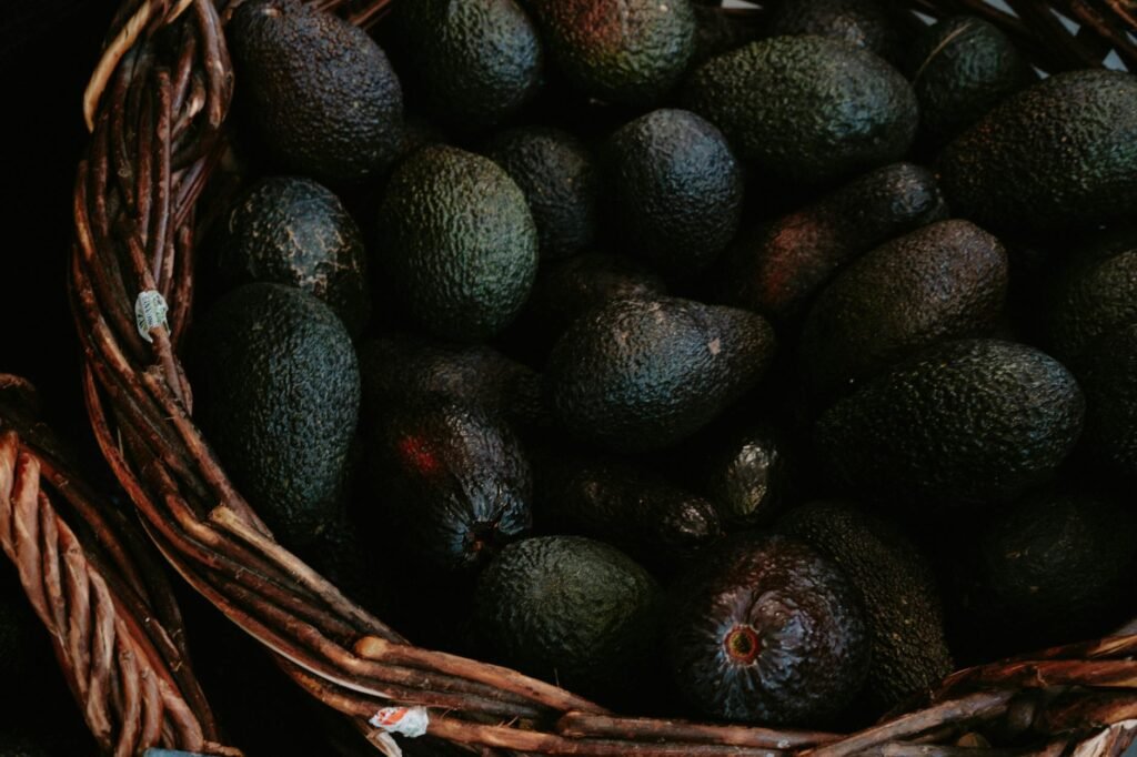 Several avocados at different ripeness stages in a grocery basket