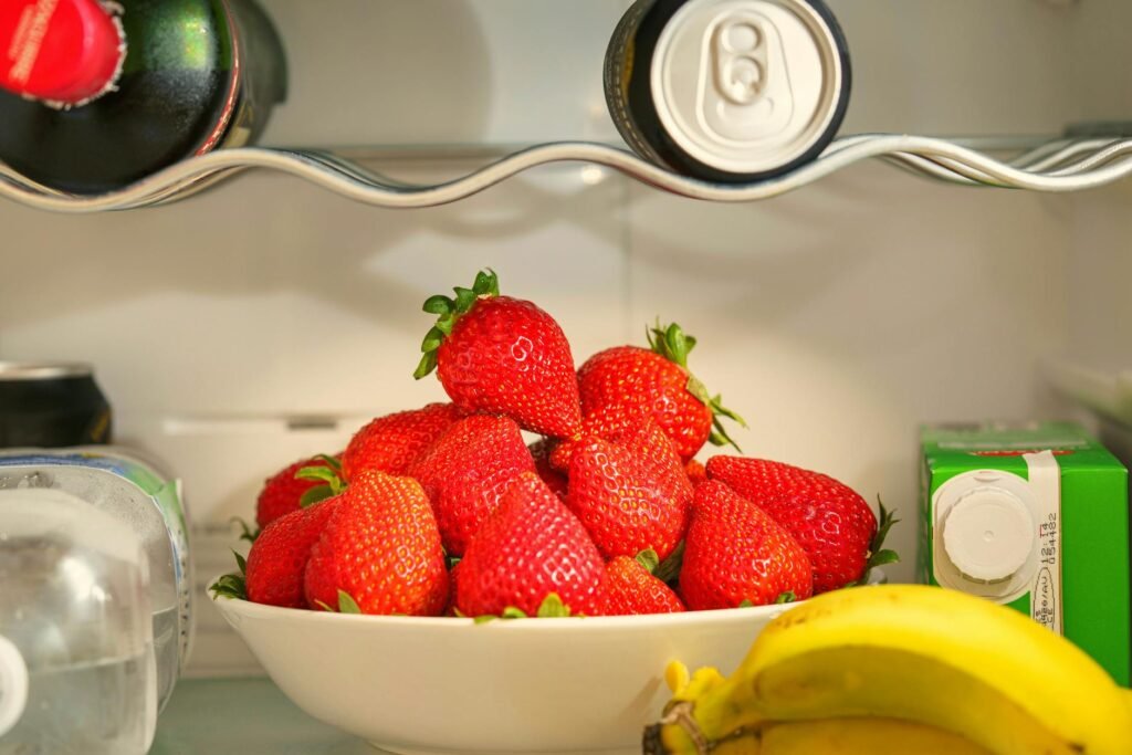 A refrigerator shelf with produce containers and a thermometer