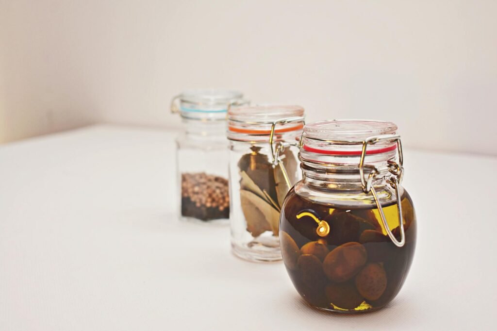 Small bottles of cooking oil stored neatly in a dark pantry shelf.