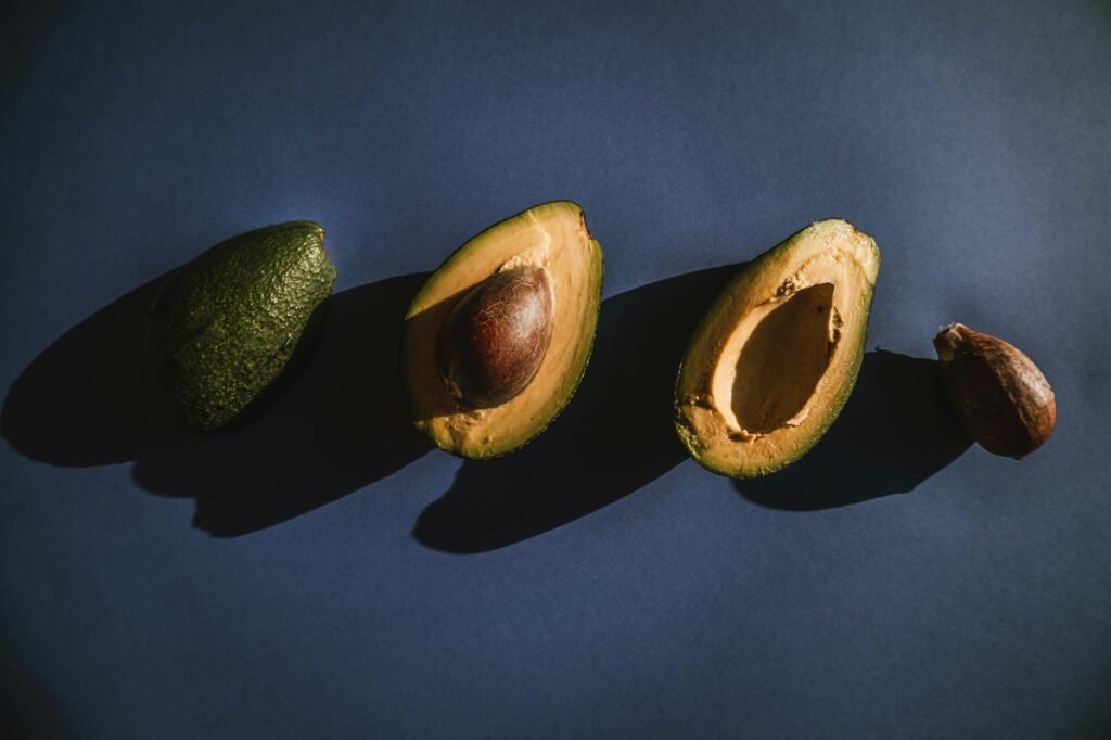 Three avocados at different ripeness stages arranged beside a handwritten meal plan.