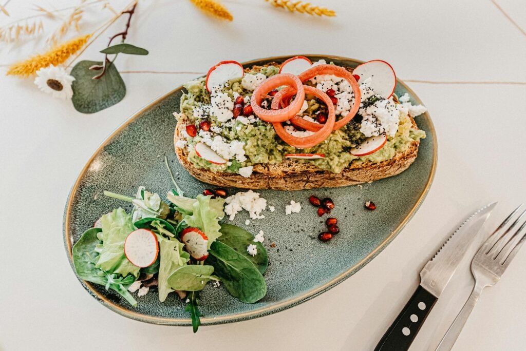 Overhead view of avocado toast on thick sourdough with lemon, radish, and flaky salt