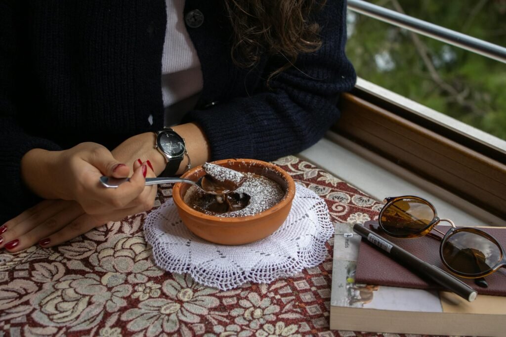A spoon dragged through a thick chocolate dessert in a glass bowl, leaving a visible line