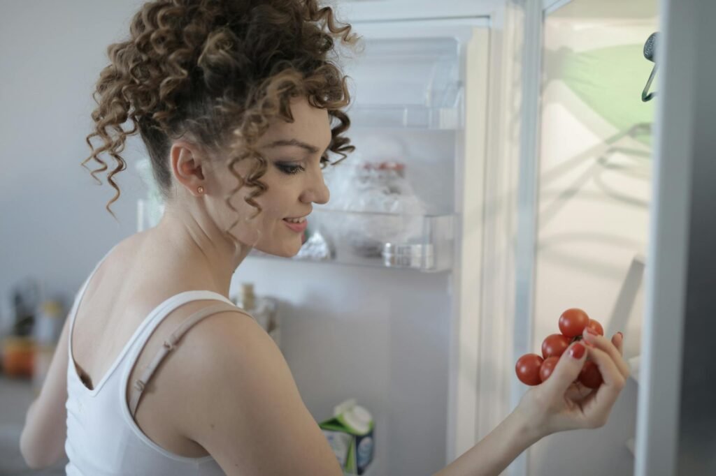 An organized refrigerator shelf with produce containers and a visible thermometer
