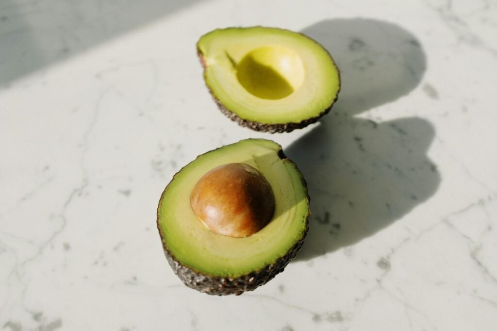 Ripe avocados on a clean cutting board, with one cut open.
