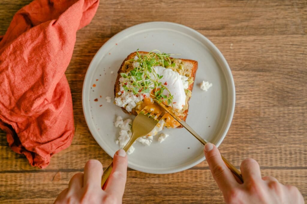 Avocado toast topped with sliced radish and chili flakes on a white plate