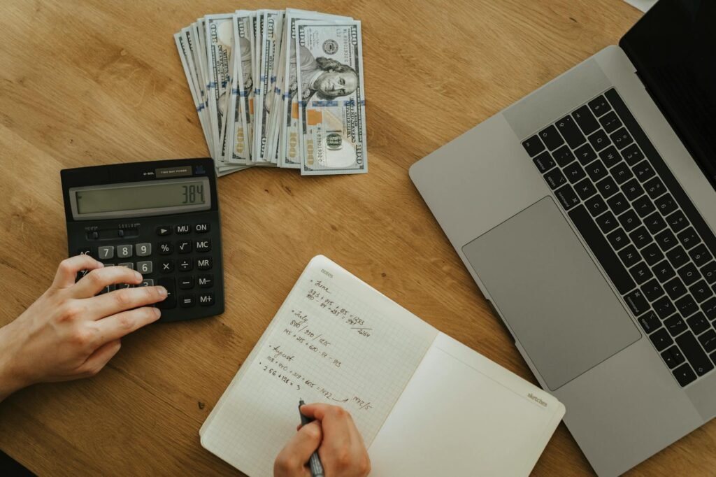 A grocery receipt, calculator, notebook, and avocados on a kitchen table