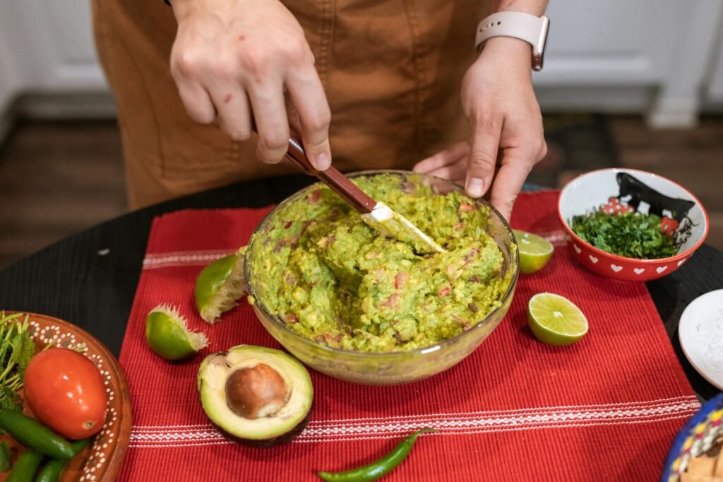 Hands mashing ripe avocado with lime juice in a small bowl