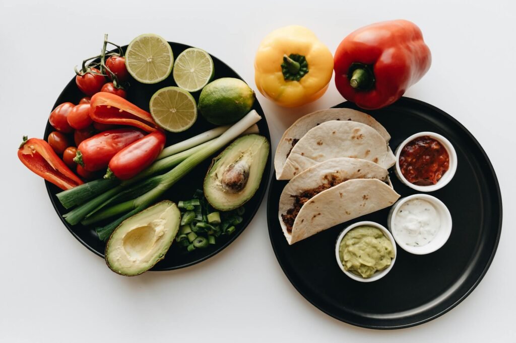 Avocados, tortillas, beans, cucumber, and scallions arranged for weekday meal prep.