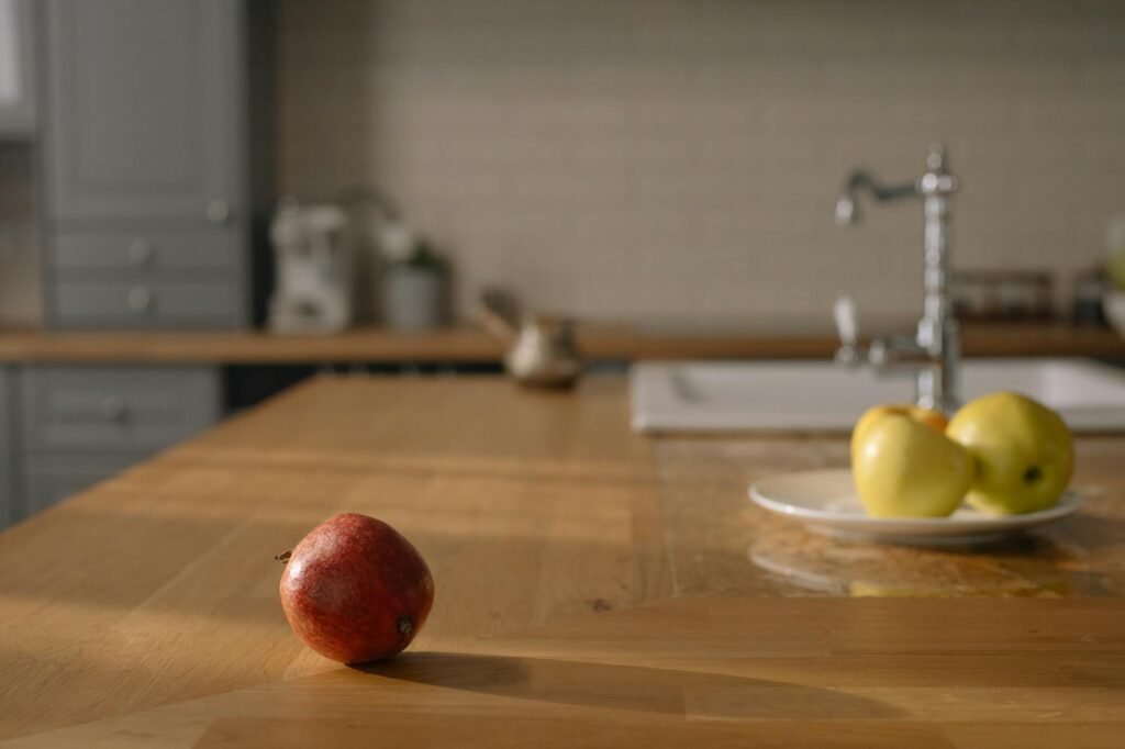 Avocados at different ripeness stages on a kitchen counter beside a brown paper bag and apple