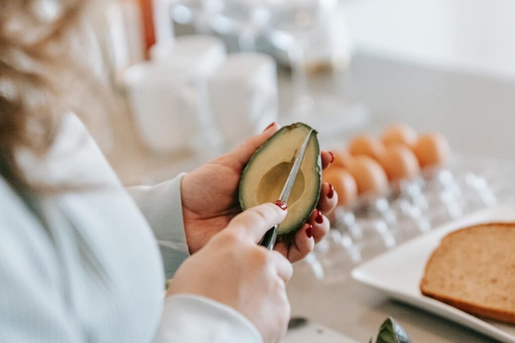 Half an avocado on a cutting board beside toast and eggs