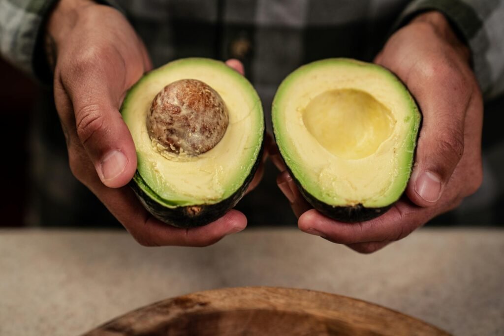 A hand gently checking avocado firmness in the palm