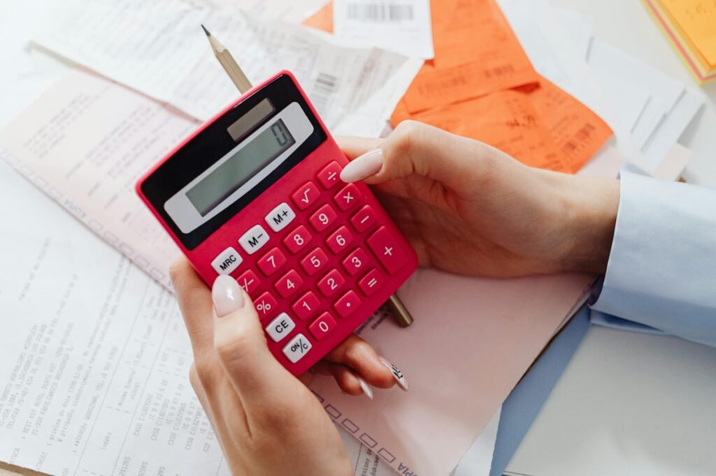 A grocery receipt and calculator placed next to avocados on a kitchen counter