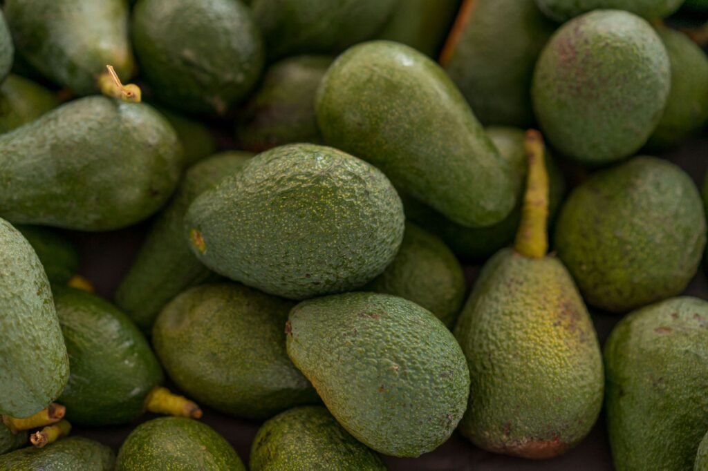 A grocery receipt next to avocados and other produce on a kitchen table.